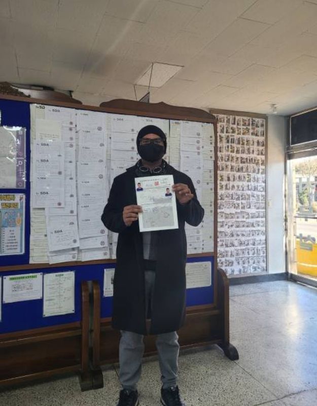 Foreign student holding a newly issued Korean driver's licence at Anyang Driving School