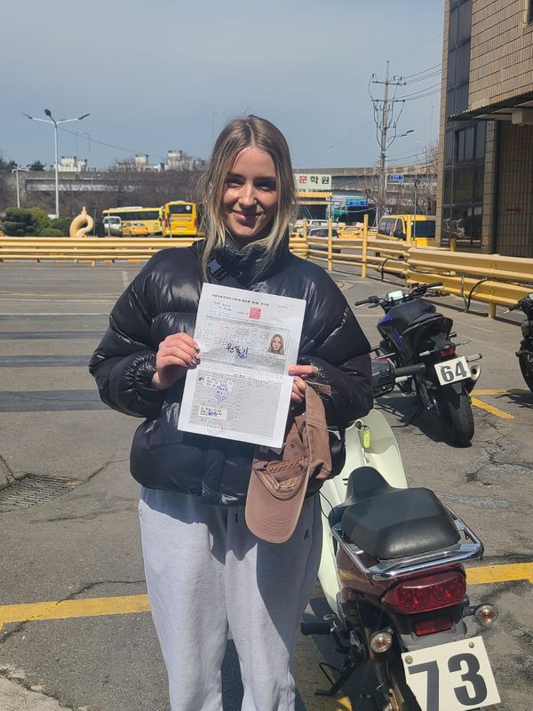 International student celebrating a road driving test pass at Anyang Driving School