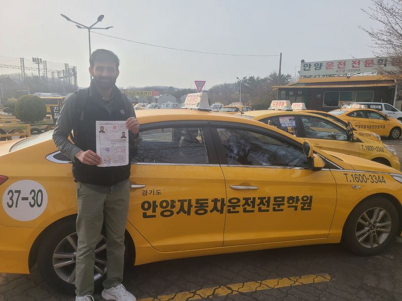 Foreign student holding a newly issued Korean driver's licence at Anyang Driving School