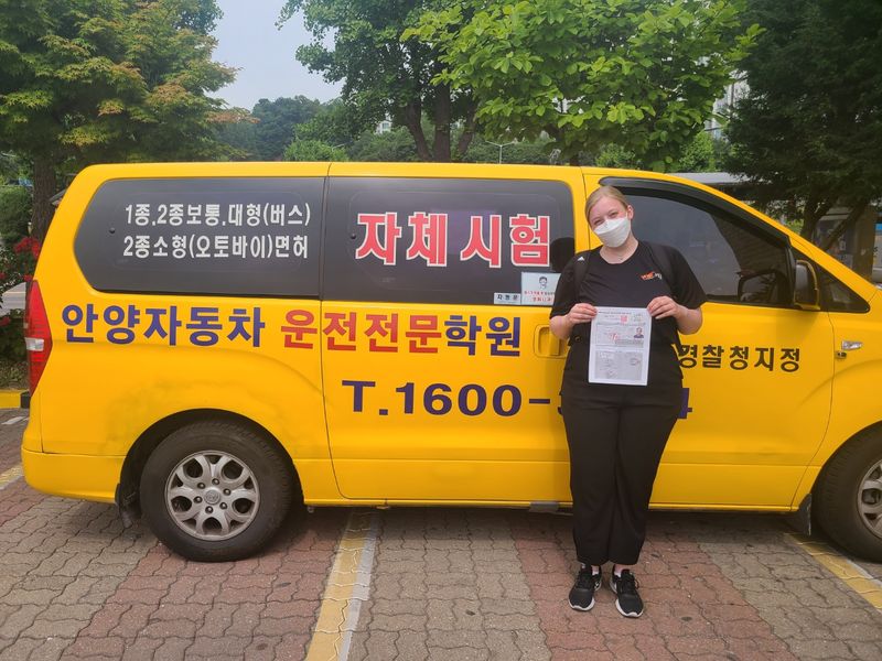 Foreign student holding a newly issued Korean driver's licence at Anyang Driving School
