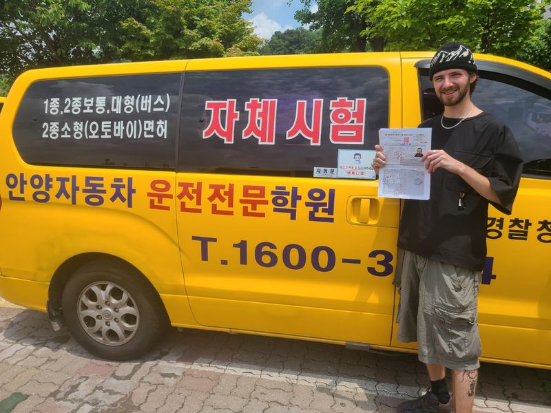 International student celebrating a road driving test pass at Anyang Driving School