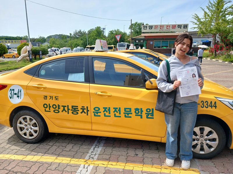 Foreign student holding a newly issued Korean driver's licence at Anyang Driving School