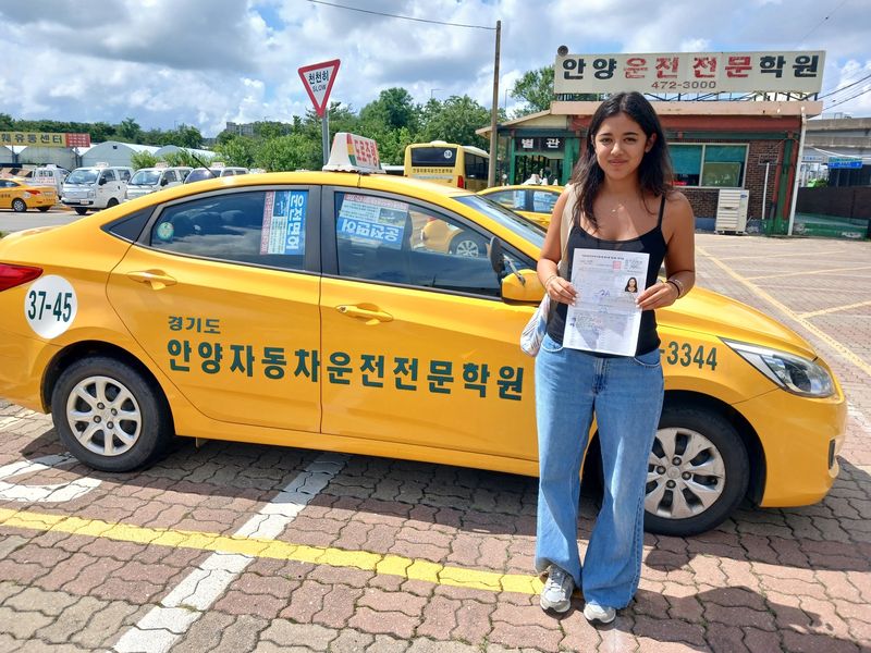 International student celebrating a road driving test pass at Anyang Driving School