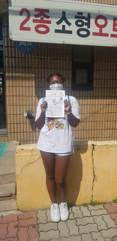 Foreign student holding a newly issued Korean driver's licence at Anyang Driving School